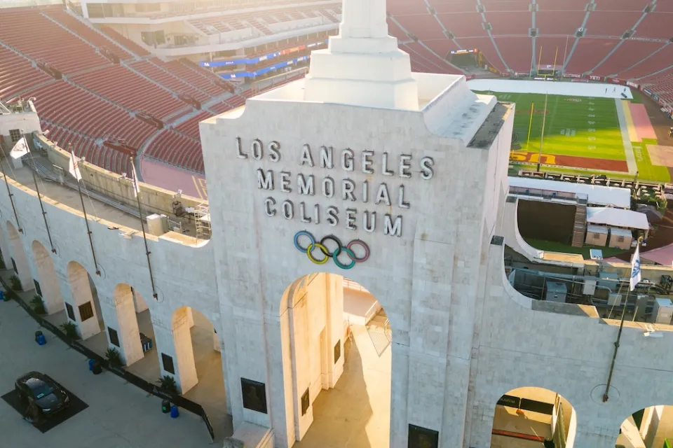 Aerial view of Los Angeles Memorial Coliseum entrance arch with name and Olympic rings.